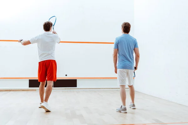 Vista trasera de dos deportistas jugando squash en pista de cuatro paredes - foto de stock