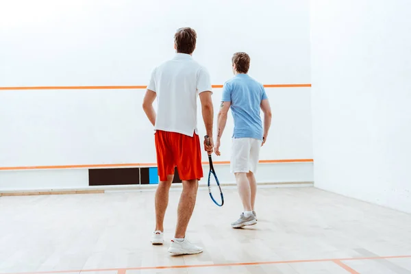 Visão traseira de dois desportistas jogando squash em quadra de quatro paredes — Fotografia de Stock