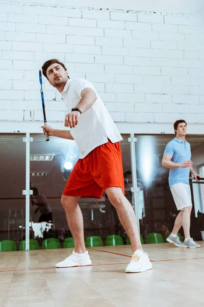 Vista completa de dos deportistas jugando squash en pista de cuatro paredes - foto de stock