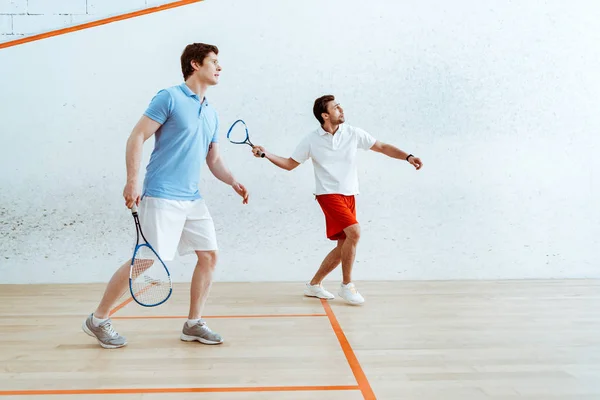 Vista completa de dos deportistas jugando squash en pista de cuatro paredes - foto de stock