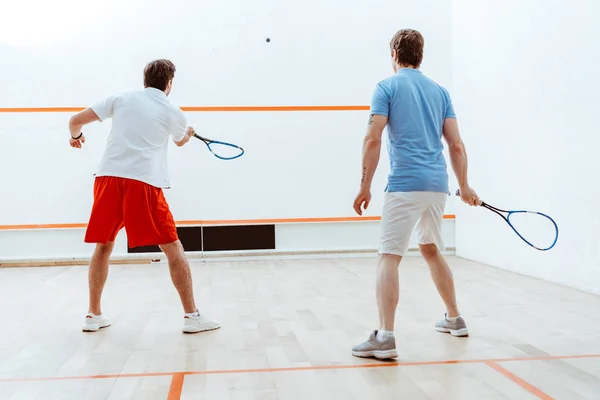 Vista posteriore di due sportivi che giocano a squash in un campo a quattro pareti — Foto stock