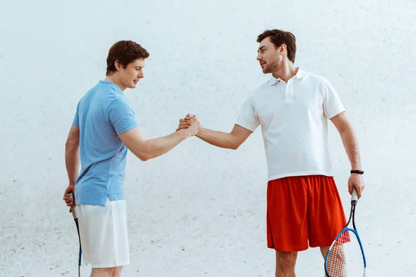 Two squash players with rackets shaking hands and looking at each other — Stock Photo