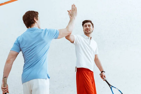 Dois jogadores de squash mostrando alto cinco sinal em quadra de quatro paredes — Fotografia de Stock