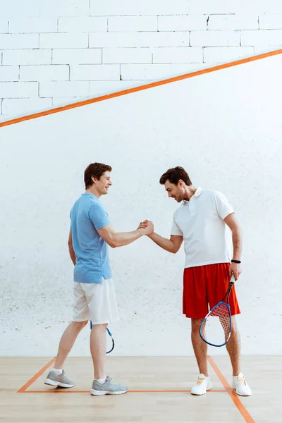 Два игрока в сквош с ракетками пожимают друг другу руки и смотрят друг на друга — стоковое фото