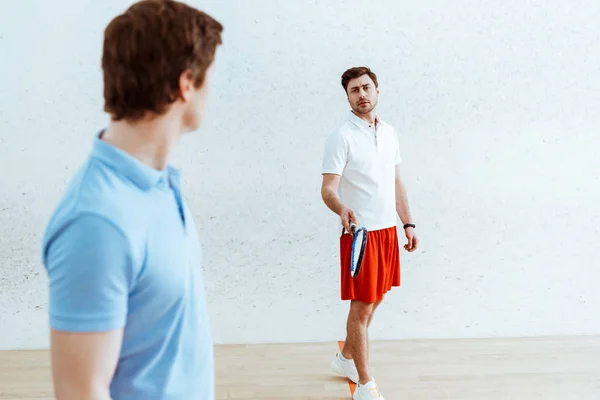 Jogadores de squash em camisa de pólo olhando um para o outro em quadra de quatro paredes — Fotografia de Stock