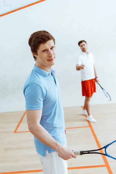 Guapo jugador de squash en polo azul mirando a la cámara - foto de stock