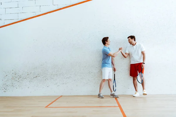 Visão completa dos jogadores de squash apertando as mãos em quadra de quatro paredes — Fotografia de Stock