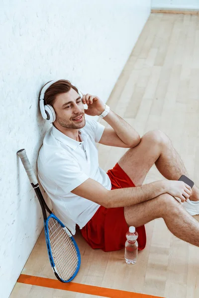Vue grand angle du lecteur de squash écoutant de la musique dans les écouteurs — Photo de stock