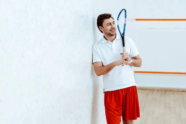 Barbudo jugador de squash sosteniendo raqueta y mirando hacia otro lado - foto de stock