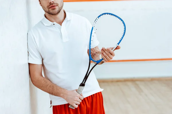 Vue partielle du joueur de squash barbu tenant une raquette dans un court à quatre murs — Photo de stock