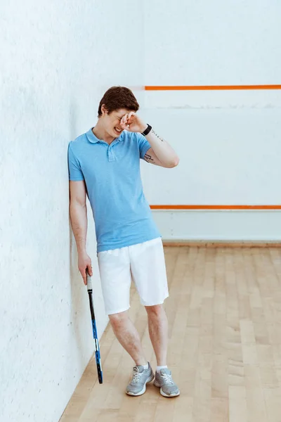 Vista a tutta lunghezza del giocatore di squash sconvolto che tocca gli occhi con la mano in un campo a quattro pareti — Foto stock
