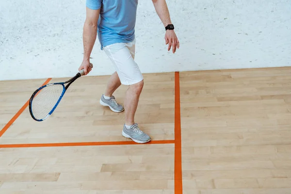 Vista parcial do desportista com raquete jogando squash em quadra de quatro paredes — Fotografia de Stock