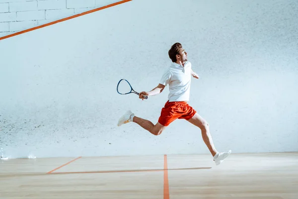 Vue pleine longueur du sportif avec raquette en cours d'exécution tout en jouant au squash — Photo de stock