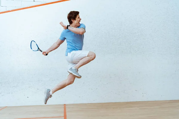 Esportista de camisa de pólo pulando enquanto joga squash em quadra de quatro paredes — Fotografia de Stock