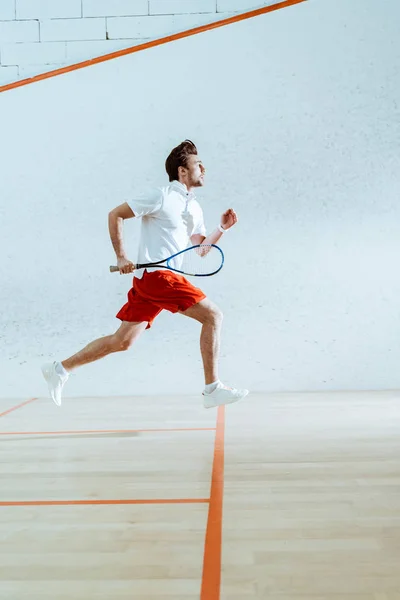 Vista completa del deportista con raqueta corriendo mientras juega squash - foto de stock