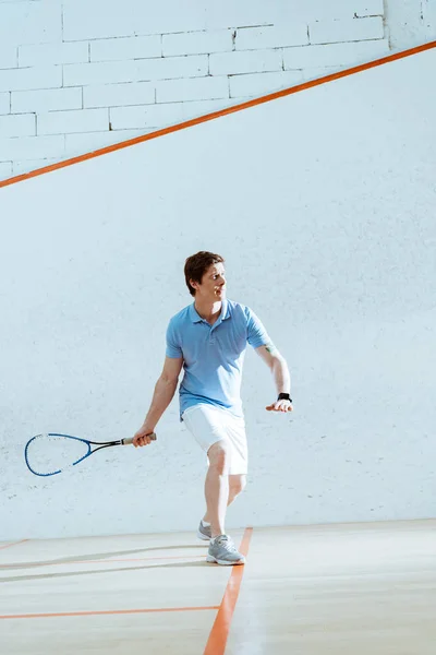 Visão de comprimento total do esportista concentrado em smartwatch jogando squash — Fotografia de Stock