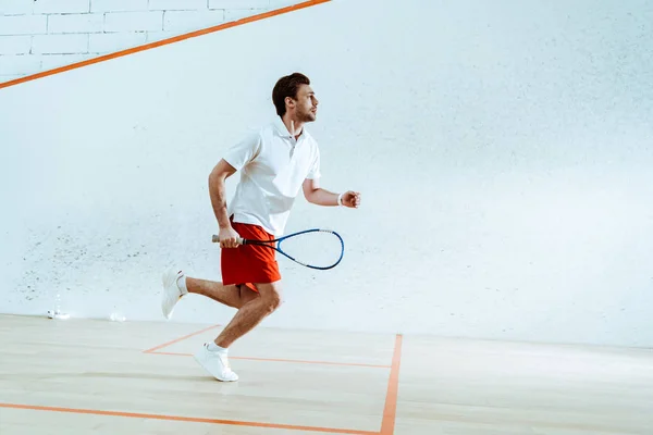 Vista a tutta lunghezza dello sportivo con racchetta in esecuzione durante la riproduzione di squash — Foto stock