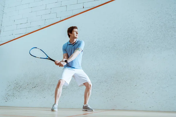 Vue pleine longueur du sportif concentré en polo bleu jouant à la courge — Photo de stock