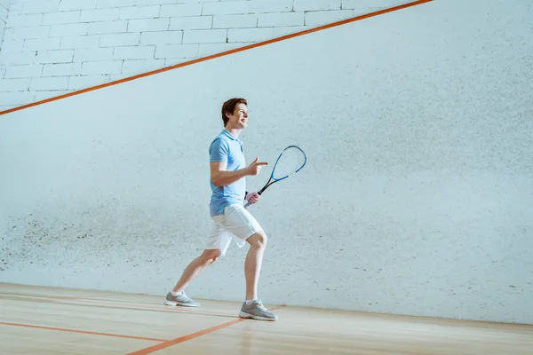 Vue pleine longueur du joueur de squash souriant pointant avec le doigt — Photo de stock