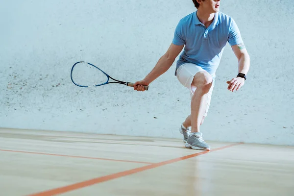 Частичный вид спортсмена в синей рубашке поло, играющего в сквош — стоковое фото