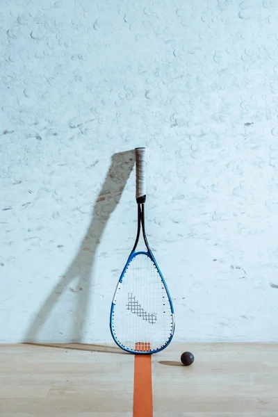 Uma raquete de squash e bola no chão de madeira em quadra de quatro paredes — Fotografia de Stock