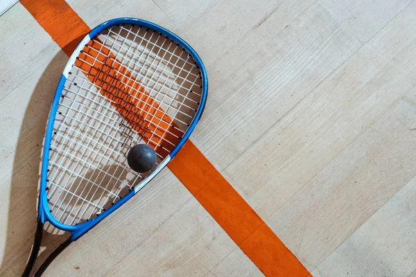 Top view of squash racket and ball on wooden surface — Stock Photo