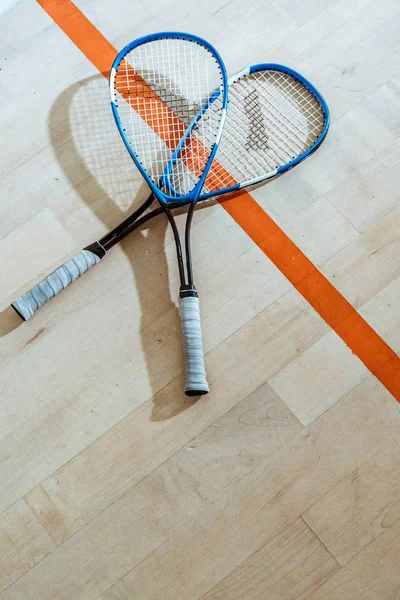 Due racchette da squash su pavimento in legno in corte a quattro pareti — Foto stock