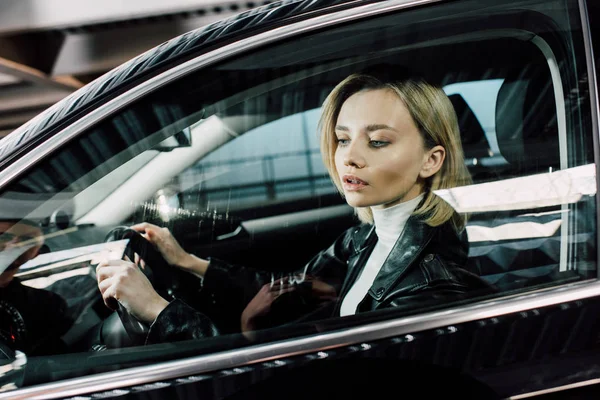 Beautiful blonde woman holding steering wheel while driving car — Stock Photo