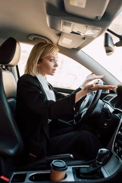 Chateado loira jovem mulher gestos enquanto sentado no carro — Fotografia de Stock