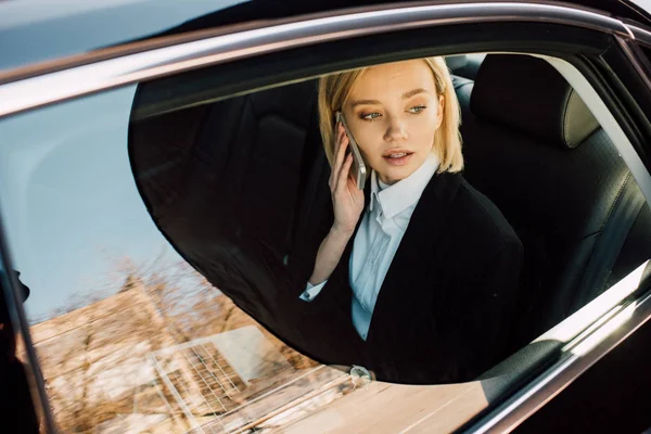 Visão aérea de mulher loira atraente falando no smartphone no carro — Fotografia de Stock