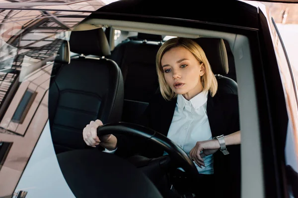 Selbstbewusste Blondine hält Lenkrad während Autofahrt — Stockfoto
