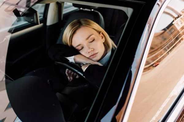 Müde blonde junge Frau schläft in modernem Auto neben Lenkrad — Stockfoto
