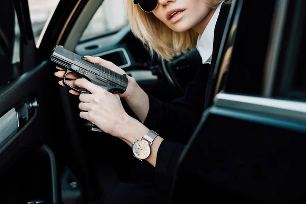Corte vista de sério loira mulher segurando arma no carro — Fotografia de Stock
