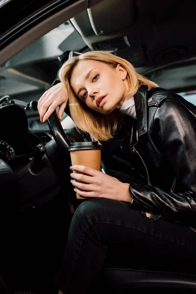 Низкий угол зрения блондинки, держащей бумажную чашку в машине — стоковое фото