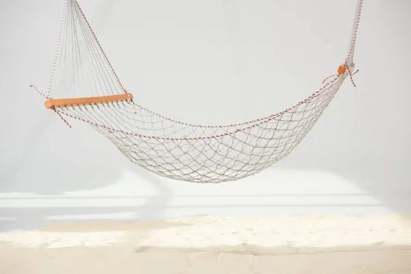 Hanging hammock made of net over sand on grey — Stock Photo