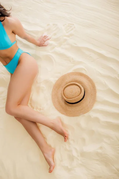 Draufsicht von Mädchen im Bikini in der Nähe von Strohhut entspannt am Strand — Stockfoto