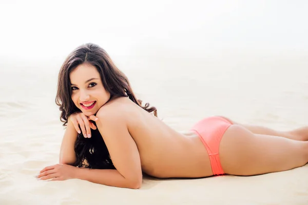 Beautiful topless Young woman looking at camera, smiling and relaxing on sandy beach — Stock Photo