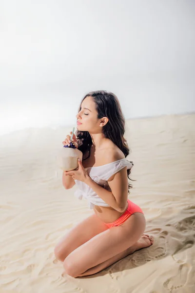 Bela menina sexy no topo branco sentado com coquetel na praia — Fotografia de Stock