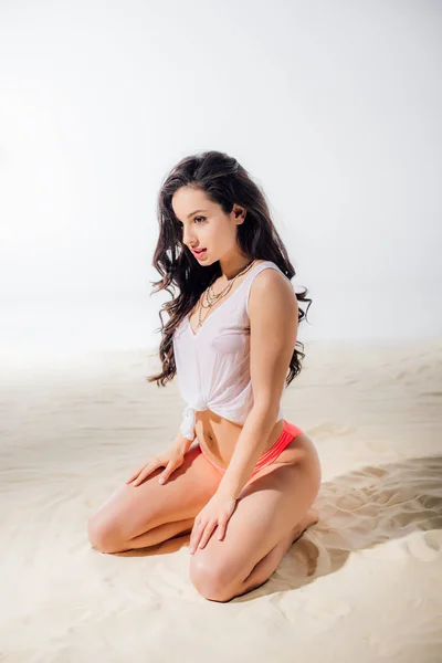 Hermosa sexy joven sentada y posando en la playa - foto de stock