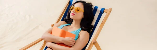 Plano panorámico de hermosa chica en bikini relajante en la tumbona con libro en la playa - foto de stock