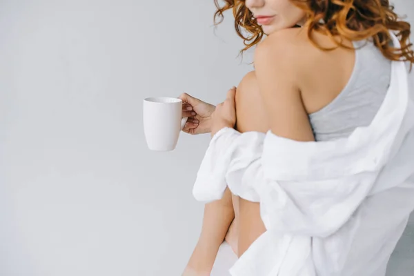 Ausgeschnittene Ansicht einer jungen Frau mit Tasse mit Kaffee auf grau — Stockfoto