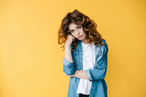 Bouleversé bouclé jeune femme regardant caméra et debout sur orange — Photo de stock