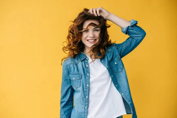 Mulher muito jovem alegre tocando o cabelo e sorrindo na laranja — Fotografia de Stock