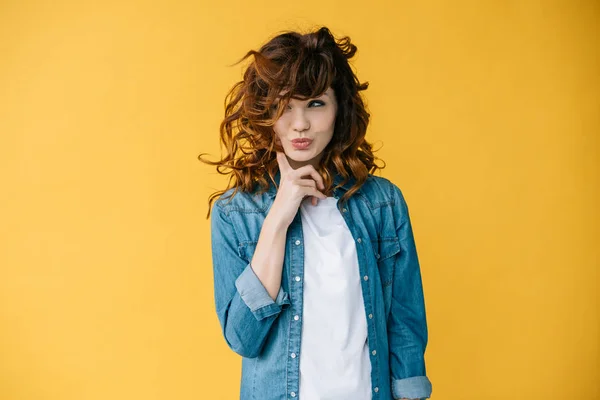 Beautiful curly young woman touching cheek while standing on orange — Stock Photo