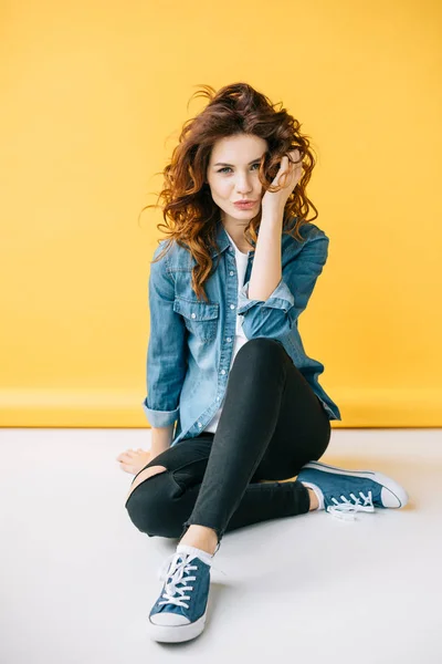 Hermosa mujer con cara de pato tocando el pelo mientras está sentado en naranja - foto de stock