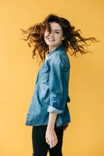 Smiling curly redhead young woman looking at camera on orange — Stock Photo