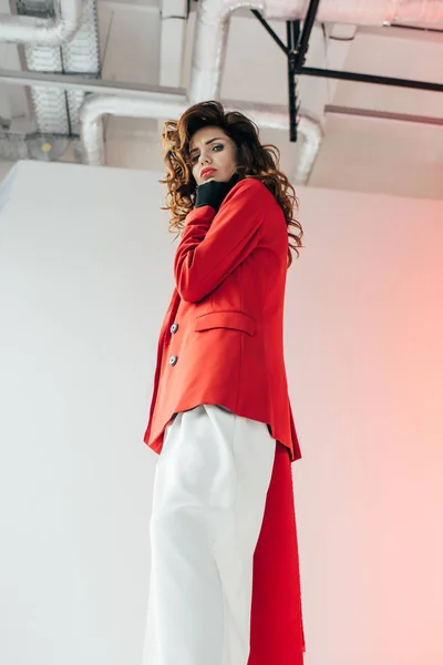 Visão de baixo ângulo de menina encaracolado elegante e atraente olhando para a câmera no cinza com gradiente — Stock Photo