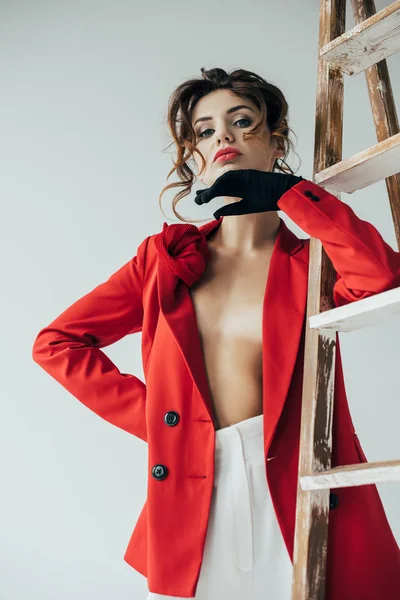 Vue à angle bas de belle rousse jeune femme debout près de l'échelle en bois sur gris — Photo de stock