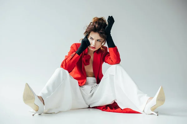 Aufgebracht und hübsche junge Frau mit roten Haaren sitzt auf weißen — Stockfoto
