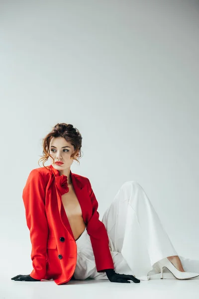 Bouleversée et jolie jeune femme bouclée aux cheveux roux assis sur blanc — Photo de stock